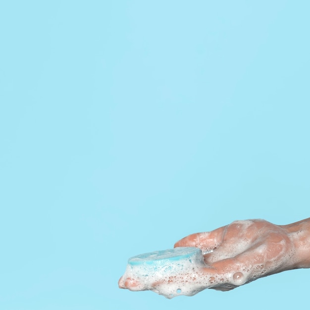 Foto gratuita persona de lado sosteniendo un jabón azul con espacio de copia