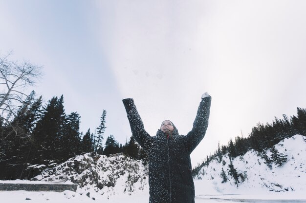 Persona lanzando nieve en el fondo del bosque