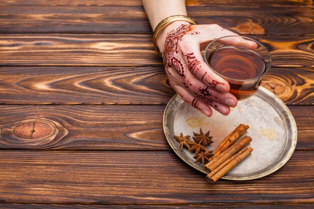 Persona con mehndi sosteniendo la taza de té en la mesa