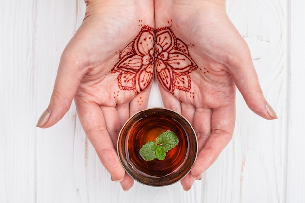 Foto gratuita persona con mehndi sosteniendo una taza de té negro