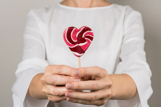 Persona mostrando piruleta en forma de corazón.