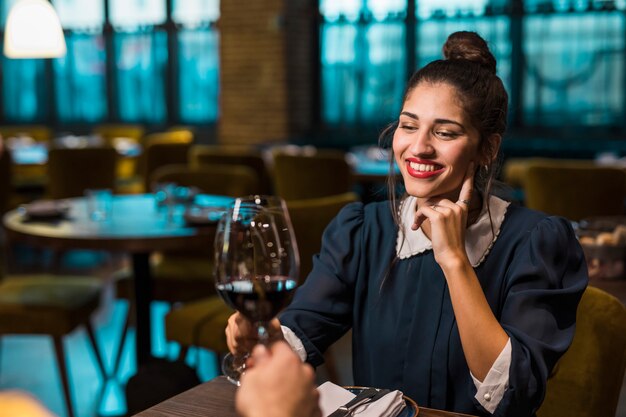 Persona y mujer feliz haciendo ruido con copas de vino en la mesa en un café