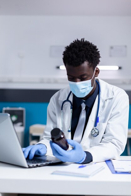 Persona negra con profesión de médico usando laptop