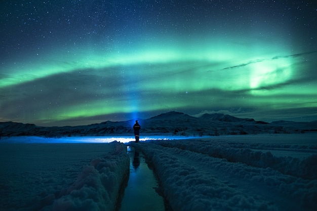 Persona de pie sobre un terreno cubierto de nieve bajo un cielo verde