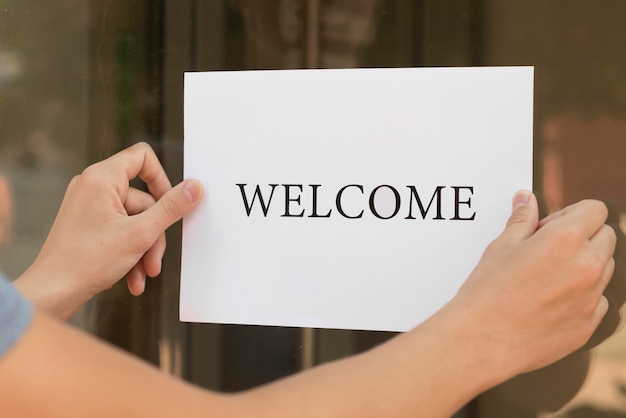 Persona poniendo un cartel de bienvenida en una puerta