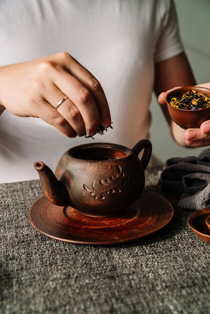 Persona poniendo hierbas de té en una tetera