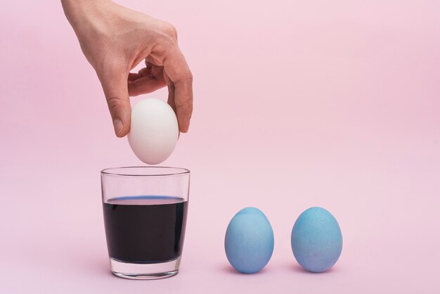 Persona poniendo huevo en vaso con pintura