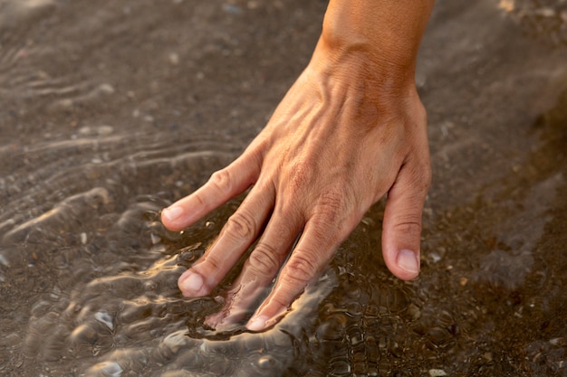 Persona poniendo su mano en el agua en la playa.