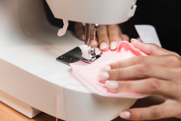 Persona de primer plano cosiendo una máscara médica con una máquina de coser