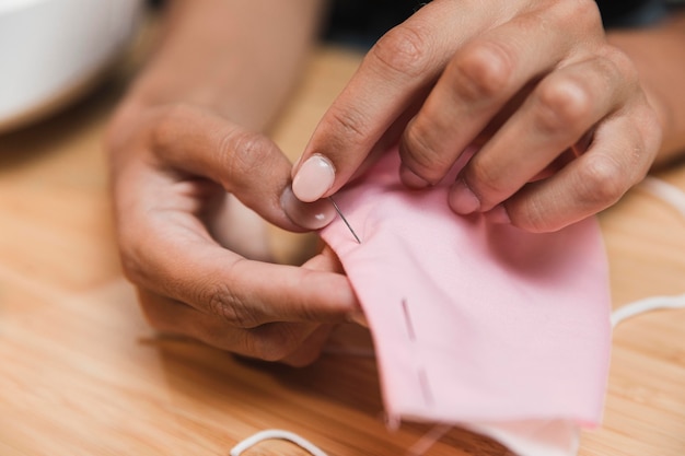 Persona de primer plano cosiendo una máscara médica