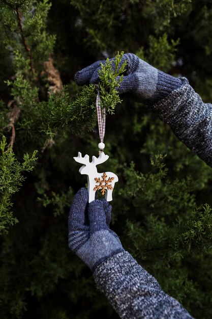 Persona de primer plano con guantes decorar el árbol de navidad con adornos