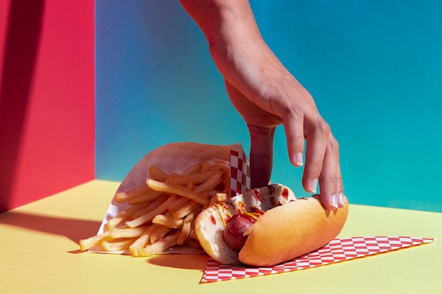 Persona de primer plano con hot dog y papas fritas