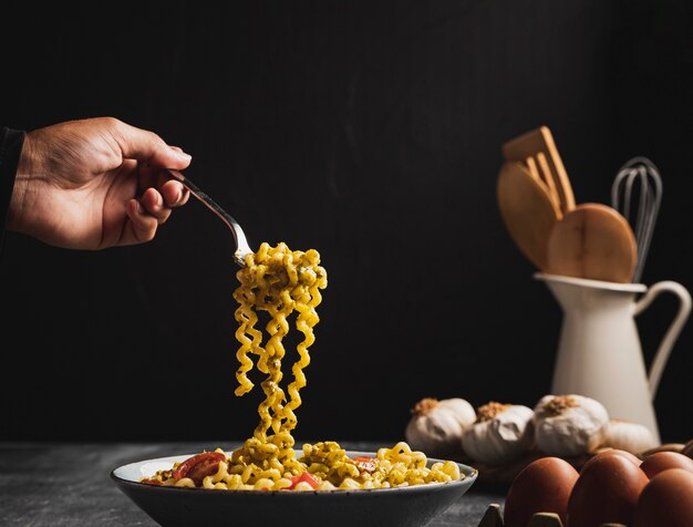 Persona de primer plano con pasta rizada con tenedor