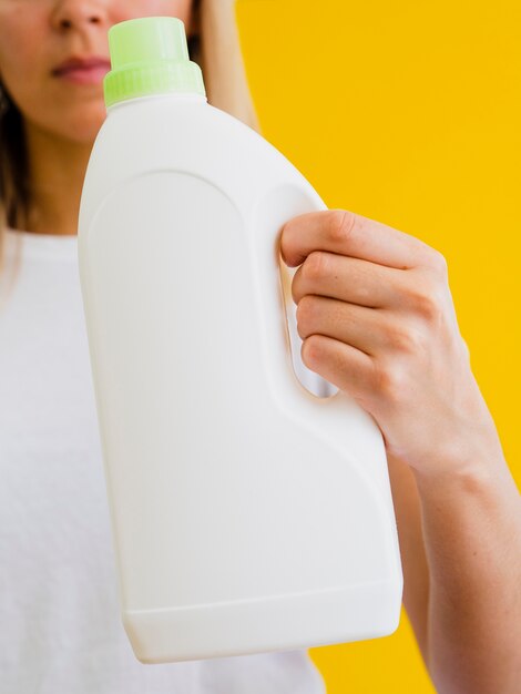 Persona de primer plano sosteniendo la botella de detergente