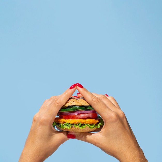Persona de primer plano sosteniendo una deliciosa hamburguesa vegetariana