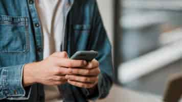 Foto gratuita persona de primer plano mediante teléfono móvil