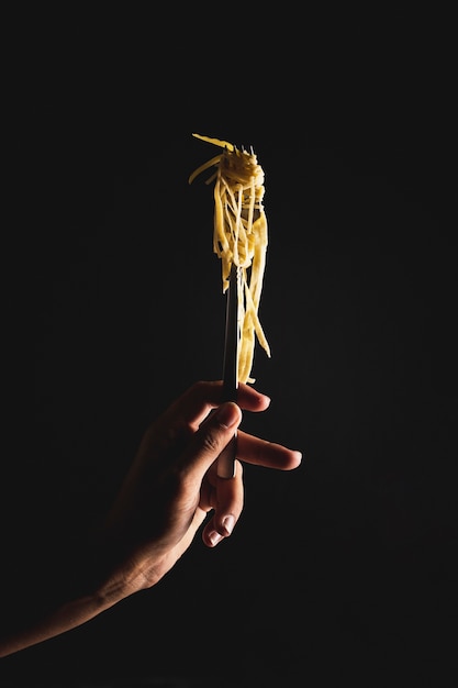 Persona de primer plano con tenedor con fideos