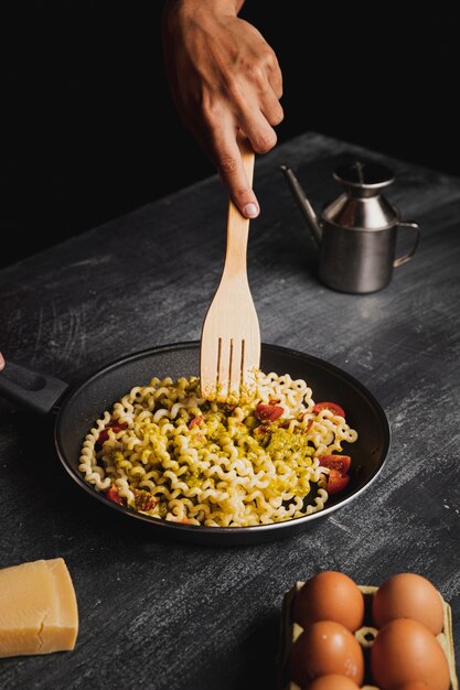 Persona de primer plano con tenedor de madera mezclando pasta