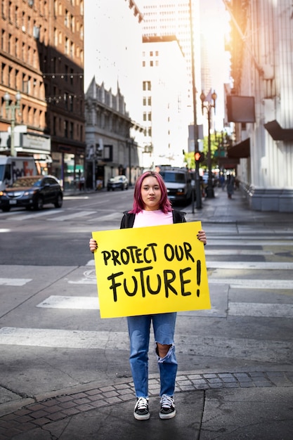 Foto gratuita persona protestando con pancarta en la ciudad por el día mundial del medio ambiente