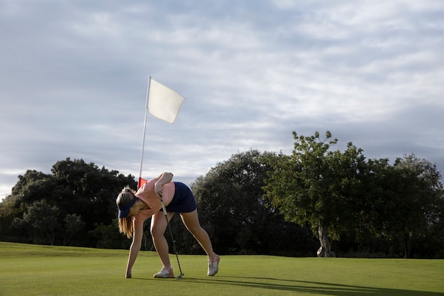 Persona que apunta a la bandera de golf