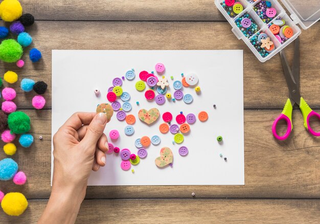 Una persona que decora el Libro Blanco con botones de colores sobre la mesa de madera