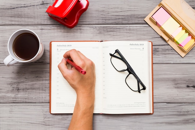 Persona que escribe en el cuaderno en la mesa