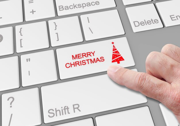 Persona que hace clic en un botón especial "Feliz Navidad" en el teclado de una computadora portátil
