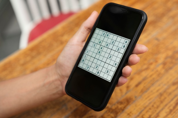 Foto gratuita persona que juega un juego de sudoku en un teléfono inteligente