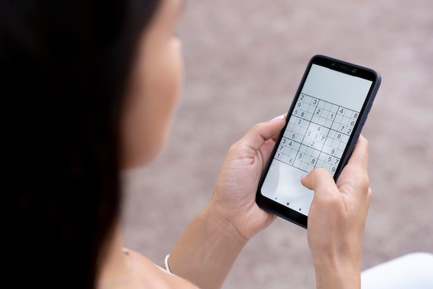 Persona que juega un juego de sudoku en un teléfono inteligente