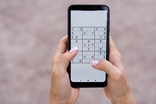 Persona que juega un juego de sudoku en un teléfono inteligente