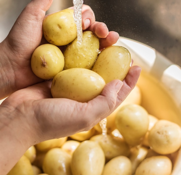 Una persona que lava las patatas debajo de agua corriente idea de la receta de la fotografía de la comida