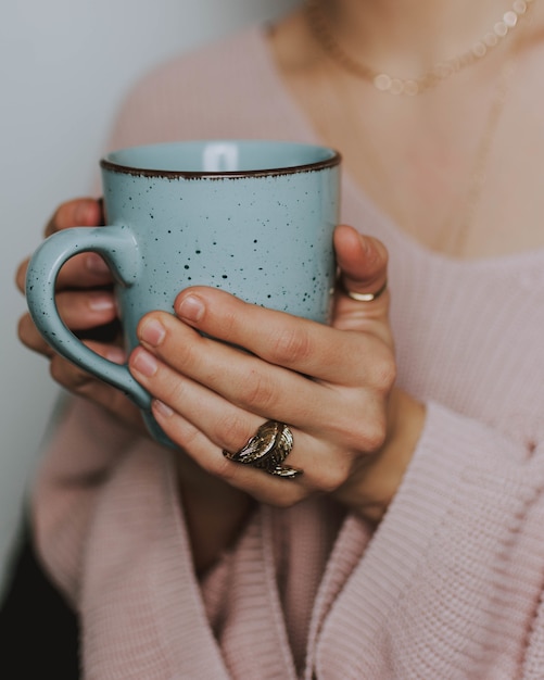 Persona que llevaba un suéter rosa con una taza azul