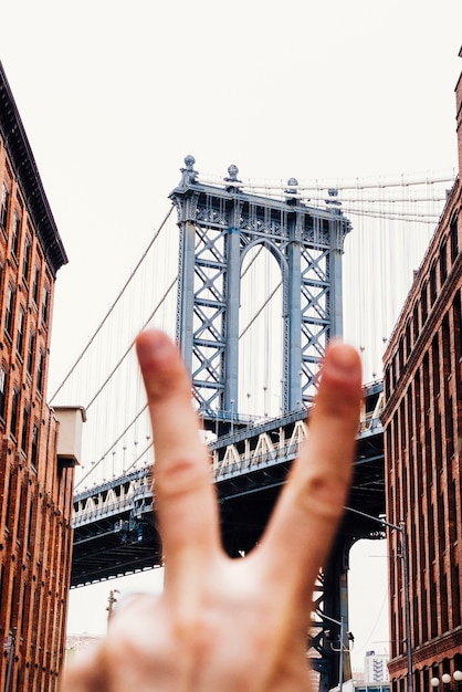 Persona que muestra el signo de la paz en el fondo del puente