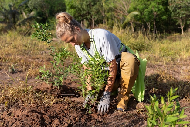 Persona que planta un árbol en el campo.