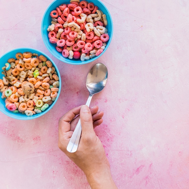 Persona que sostiene una cuchara cerca de los tazones con cereales