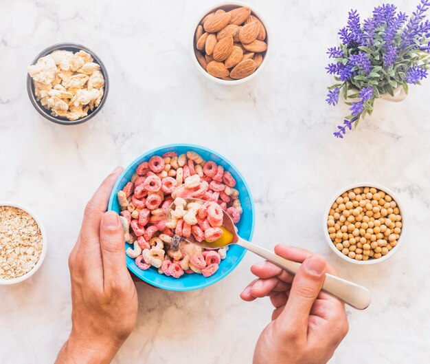 Persona que sostiene una cuchara con cereal encima del tazón azul