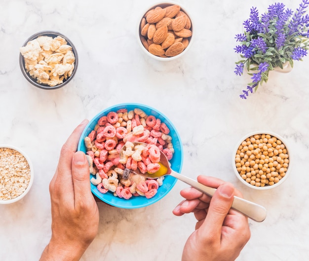 Persona que sostiene una cuchara con cereal encima del tazón azul