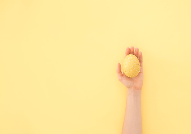 Persona que sostiene el huevo de Pascua amarillo en la mano