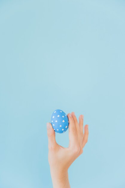 Persona que sostiene el huevo de Pascua azul en la mano
