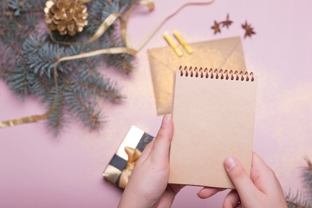 Persona que sostiene la libreta encima de la mesa de Navidad