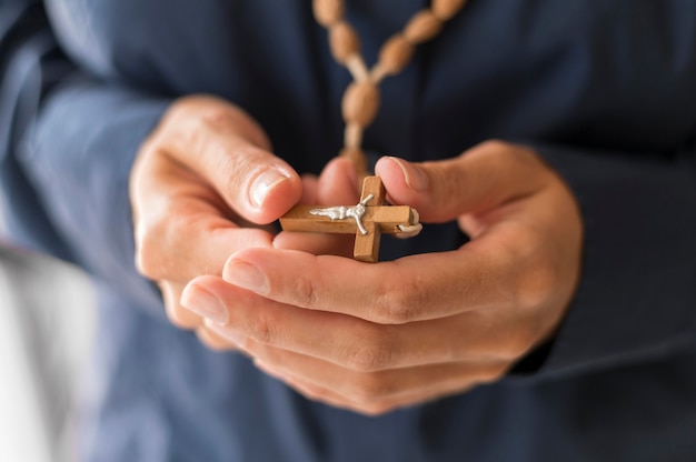 Persona que sostiene el rosario con cruz