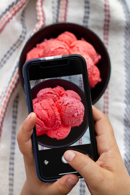 Persona que toma una foto de un helado en un plato con un teléfono inteligente