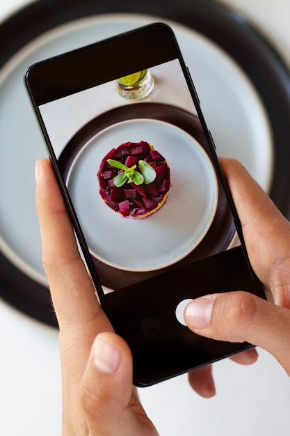 Persona que toma la foto del postre de frutas con teléfono inteligente