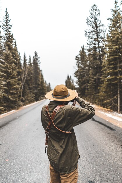 Persona que toma la fotografía de la carretera entre árboles