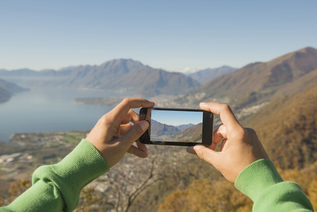 Persona que toma una fotografía de las montañas y el lago alpino Maggiore en Suiza