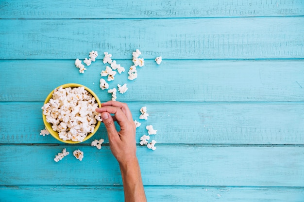 Persona que toma palomitas de maíz del cuenco