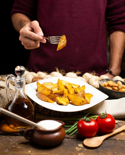 Una persona que toma patatas fritas con un tenedor.