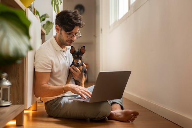 Foto gratuita persona que trabaja desde casa con perro mascota