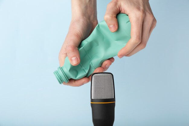 Persona que usa una botella de plástico cerca del micrófono para asmr