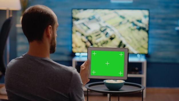 Persona que usa tableta moderna horizontalmente para pantalla verde